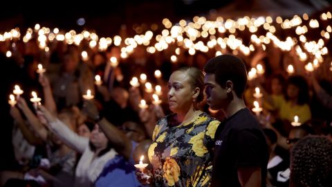 Veronica Hartfield, stands with her son, Ayzayah during a candlelight vigil for her husband, Charleston. 