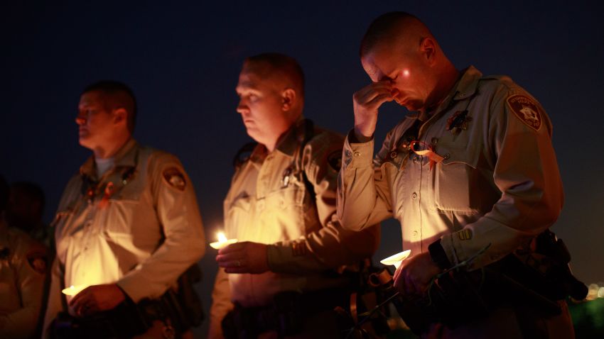 LAS VEGAS, NV - OCTOBER 5: Police officer colleagues of Las Vegas Metropolitan Police Department Officer Charleston Hartfield hold candles during a vigil for Hartfield at Police Memorial Park on October 5, 2017 in Las Vegas, Nevada. Hartfield, who was off duty at the Route 91 Harvest country music festival on October 1, was killed when Stephen Paddock opened fire on the crowd killing at least 58 people and injuring more than 450. The massacre is one of the deadliest mass shooting events in U.S. history. (Photo by Drew Angerer/Getty Images)