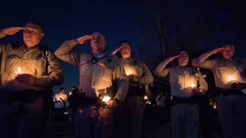 Las Vegas police officers salute during Thursday's candlelight vigil.