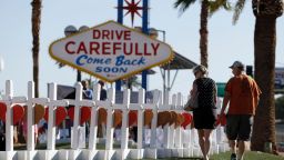 People walk by crosses placed near Las Vegas' famous sign Thursday, Oct. 5, 2017, in Las Vegas. The crosses are in honor of those killed when Stephen Craig Paddock broke windows on the Mandalay Bay resort and casino and began firing with a cache of weapons at a country music festival Sunday. Dozens of people were killed and hundreds were injured. (AP Photo/Gregory Bull)