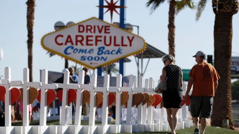 People near Las Vegas' famous sign walk by the row of crosses created by retired carpenter Greg Zanis.