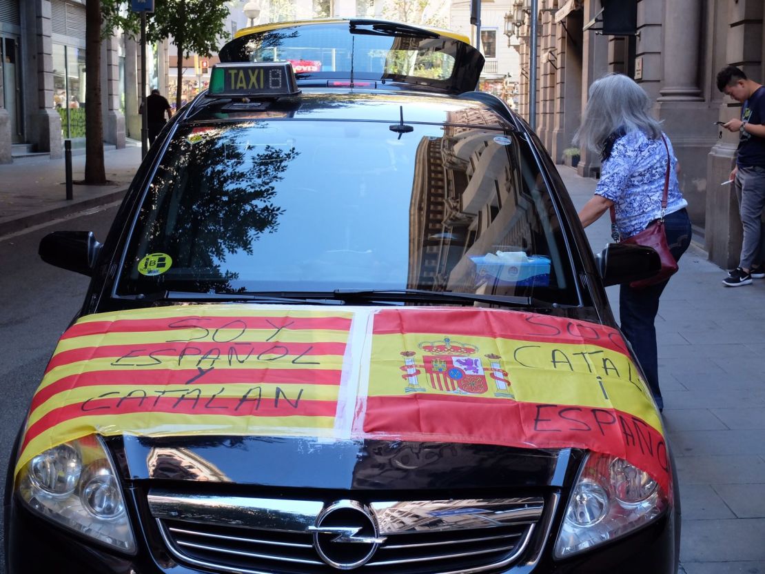 A car is adorned with Spanish and Catalan flags reading "I am Spanish and Catalan" and "I am Catalan and Spanish."
