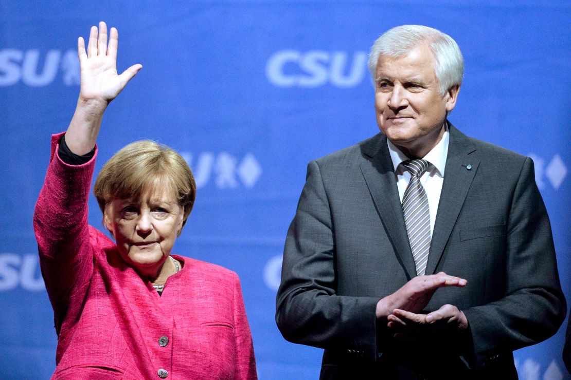 Angela Merkel waves to supporters as Bavarian governor and head of the Bavarian Christian Democrats (CSU) Horst Seehofer looks on