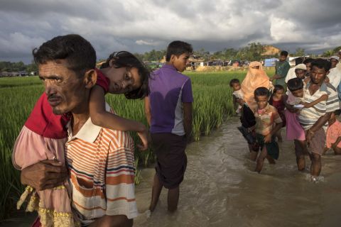 Rohingya refugees carry their belongings across muddy waters at a camp on October 5.