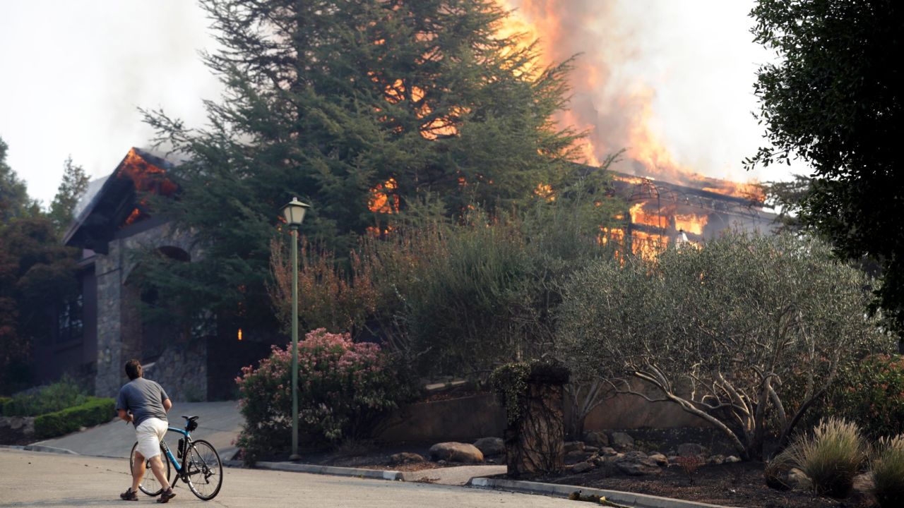 A man passes a burning house in Napa on October 9.