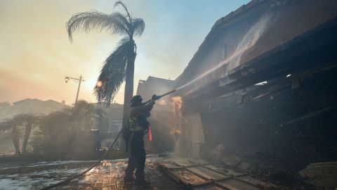 A firefighter douses flames at a home in Anaheim on October 9.