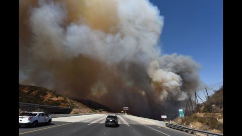 Police cars block State Route 241 as smoke rises above Orange on October 9.