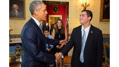 President Barak Obama shakes Camryn Kellogg's hand while sister Chiara and brother Luca look on