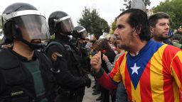 SANT JULIA DE RAMIS, SPAIN - OCTOBER 01: A man dressed in the Catalonian flag confronts officers as police move in on the crowds as members of the public gather outside to prevent them from stopping the opening and intended voting in the referendum at a polling station where the Catalonia President Carles Puigdemont will vote later today on October 1, 2017 in Sant Julia de Ramis, Spain. More than five million eligible Catalan voters are estimated to visit 2,315 polling stations today for Catalonia's referendum on independence from Spain. The Spanish government in Madrid has declared the vote illegal and undemocratic.  (Photo by David Ramos/Getty Images)
