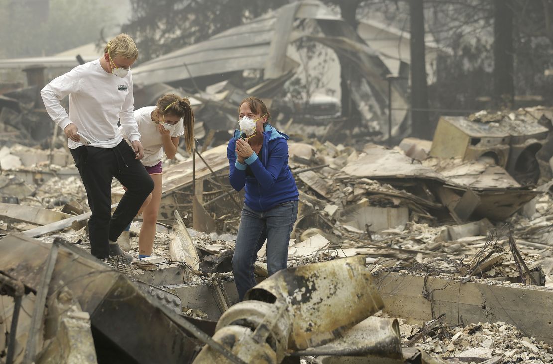 Mary Caughey, in blue, reacts after finding her wedding ring in debris at her destroyed home in Kenwood, California, on October 10.
