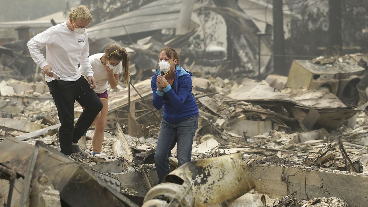 Mary Caughey, in blue, reacts after finding her wedding ring in debris at her destroyed home in Kenwood, California, on October 10.