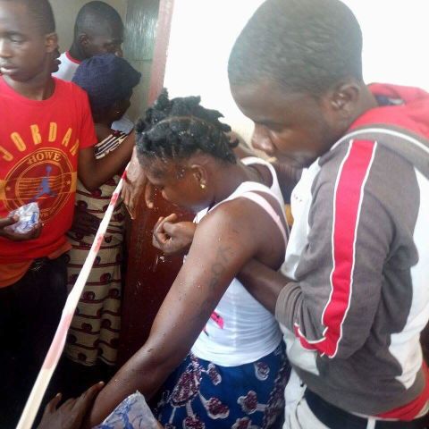 A female voter is held up after fainting in line at the School of Christ polling center in Weala, Margibi County. She had been waiting to vote since 5am in the morning. <br /><br />Credit: Local Voices Liberia/Emmanuel Tophic Degleh