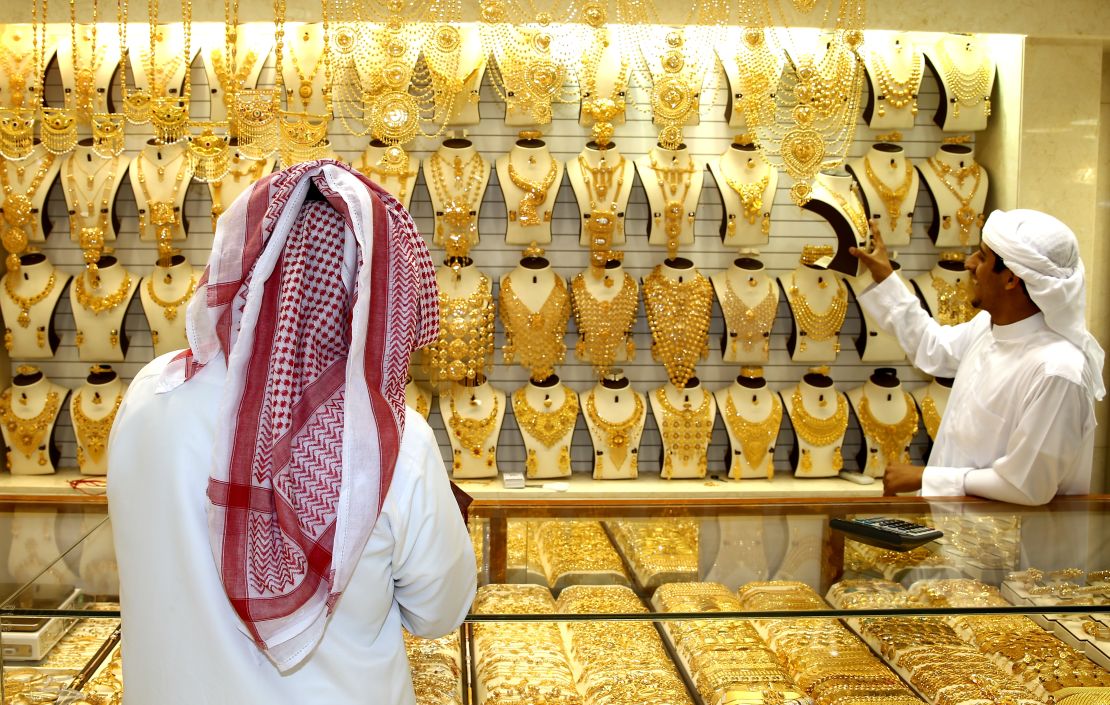 A gold merchant entices a potential customer with his jewelry at the Dubai Gold Souk in Dubai.