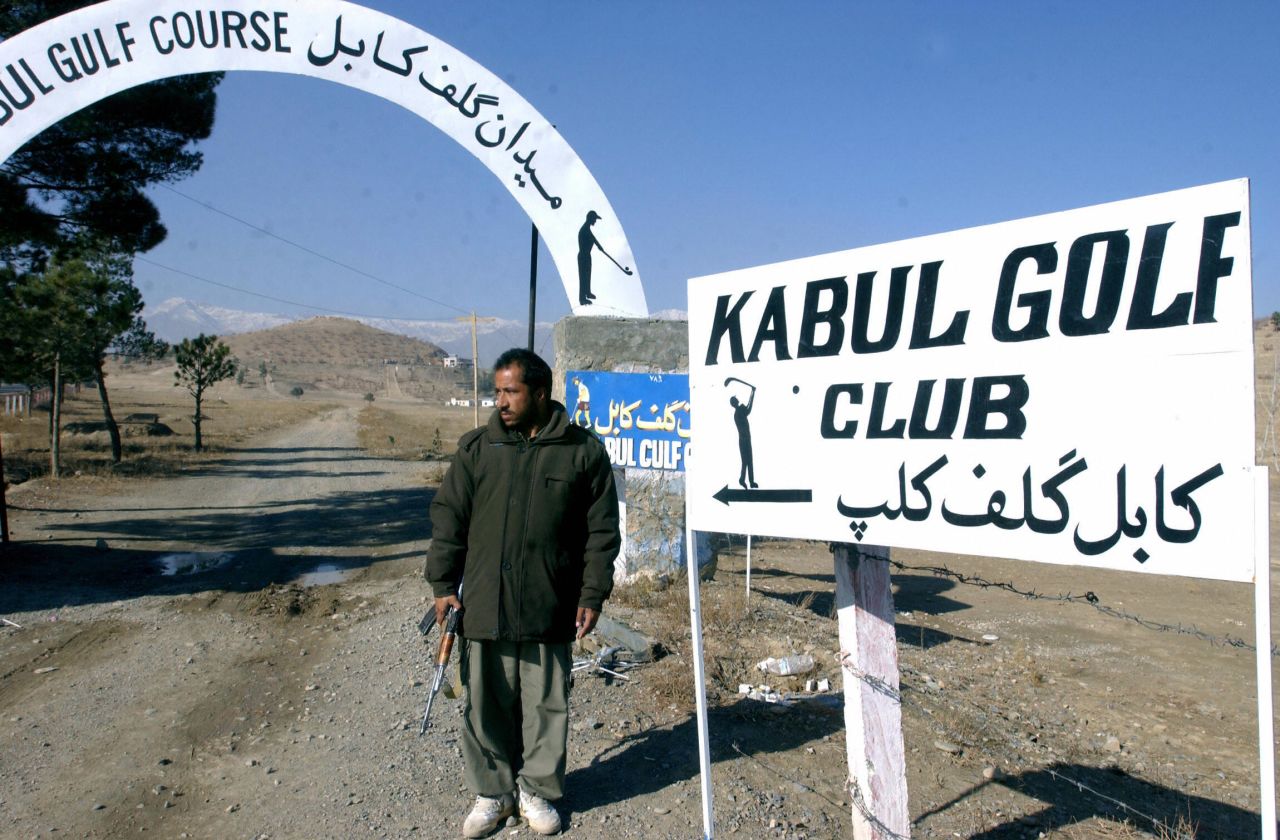 Kabul Golf Club describes itself as the "best and only" course in Afghanistan and promises "golf with an attitude." An armed security guard stands beside the entrance. 