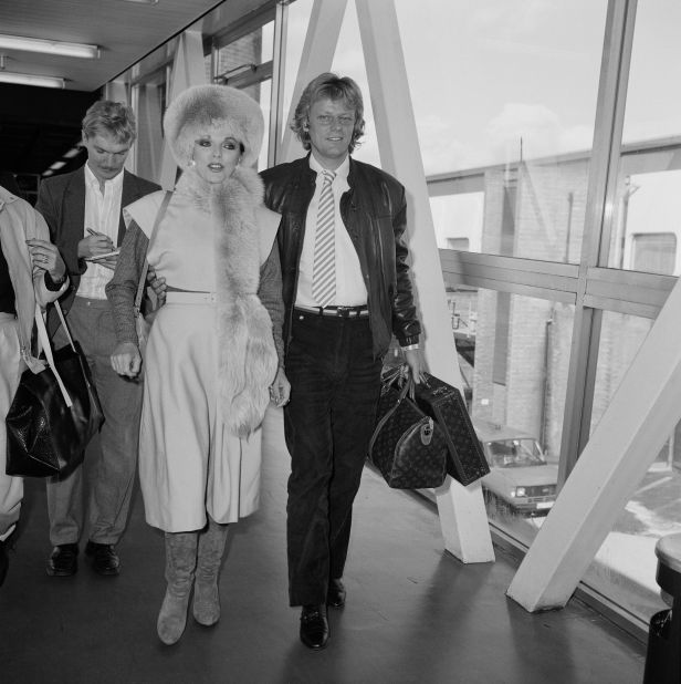 English actress Joan Collins at a London airport with her fiance, Swedish pop singer Peter Holm in 1984.