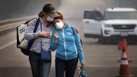 Colby Clark, left, comforts her mother, Bonnie Trexler, after law enforcement escorted them to Trexler's home in Napa, California, to retrieve medicine and personal items on Wednesday, October 11. Trexler was one of the lucky few in her neighborhood whose home was spared. Deadly wildfires have been tearing through the state, destroying homes and businesses and prompting evacuation orders.