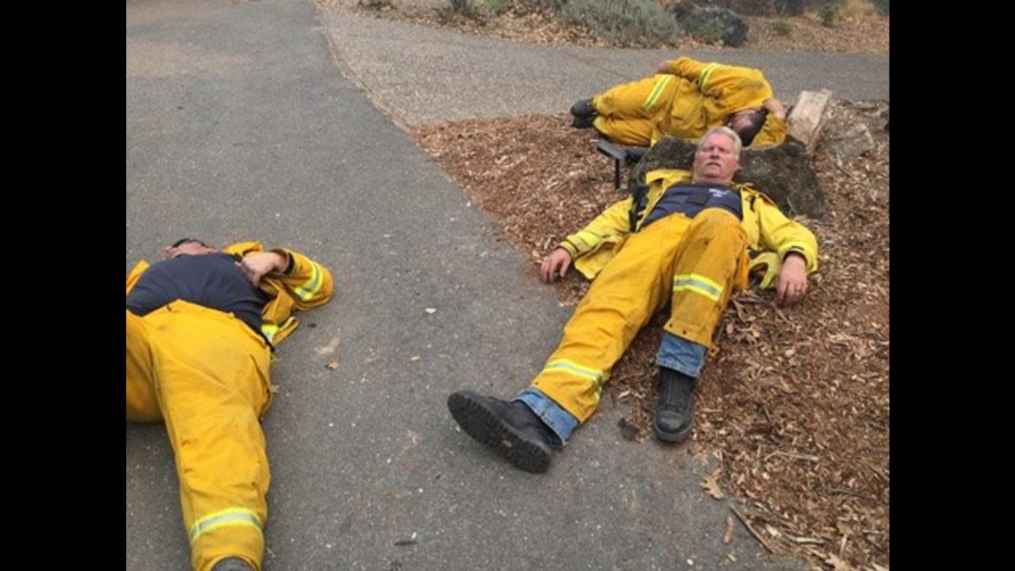 Firefighters with the Sebastopol Fire Department use the ground and a rock as a bed to get some rest.