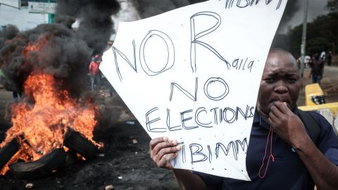 An opposition supporter stands near a pile of burning tires during a protest in Kisumu on Wednesday.