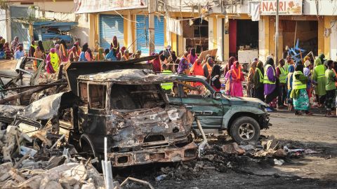 People gather near burnt vehicles a day after the explosions.