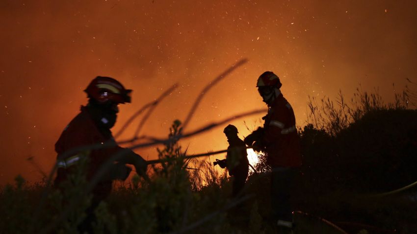 Firefighters battle a wild fire raging near houses on the outskirts of Obidos, Portugal, in the early hours of Monday, Oct. 16 2017. Hundreds of forest fires spread across Portugal fueled by high temperatures, strong winds and a persistent drought. (AP Photo/Armando Franca)