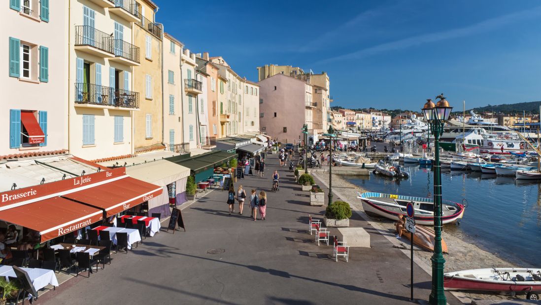 <strong>Promenade:</strong> Visitors stroll along the promenade at Saint-Tropez's port, where sailboats share space with luxury yachts.