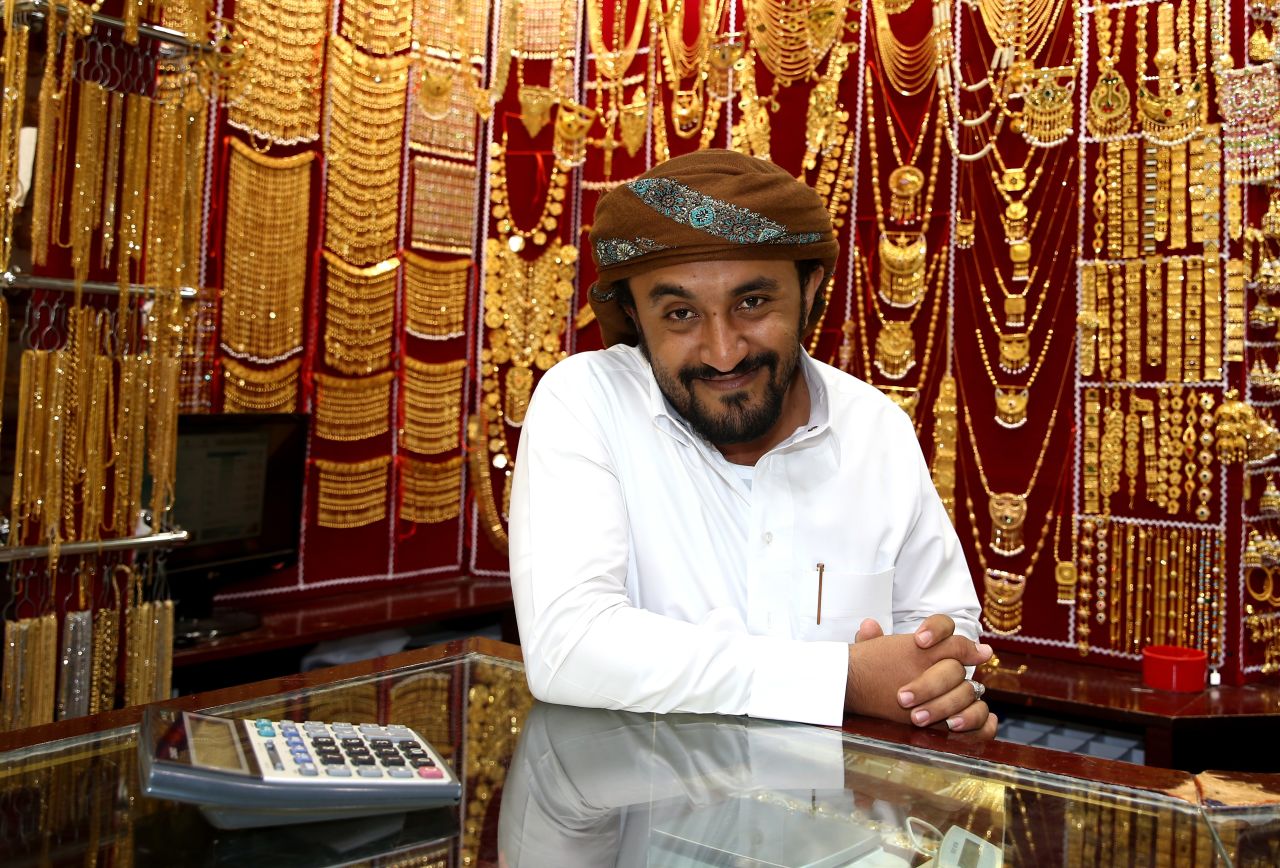A gold merchant poses with his jewelry at the Dubai Gold Souk. In the lead up to the Indian wedding season traders experience a spike in demand as soon-to-be-weds and their families buy gold jewelry for the occasion.
