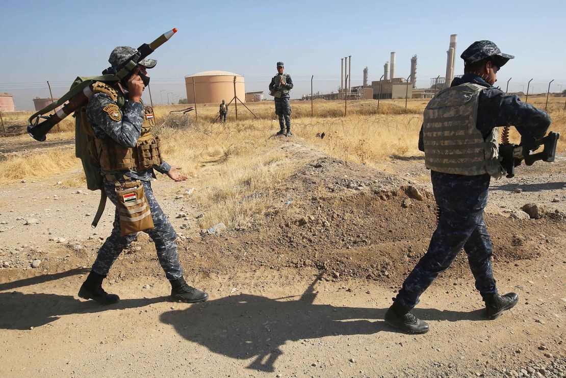 Iraqi forces pass an oil production plant Monday as they head toward Kirkuk. 
