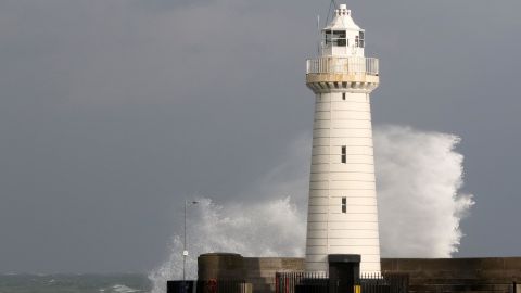 A wave crashes behind Donaghadee lighthouse in Northern Ireland on October 16, 2017.
