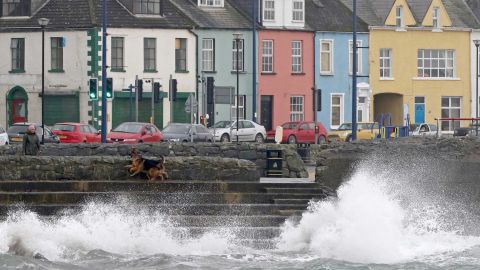 A woman walks her dogs along the sea in the coastal village of Donaghadee, Northern Ireland, on October 16, 2017.