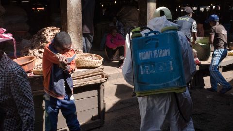 A boy covers his mouth as a council worker sprays disinfectant during the clean-up of the market in the Anosibe district, one of the most unsalubrious districts of Antananarivo.