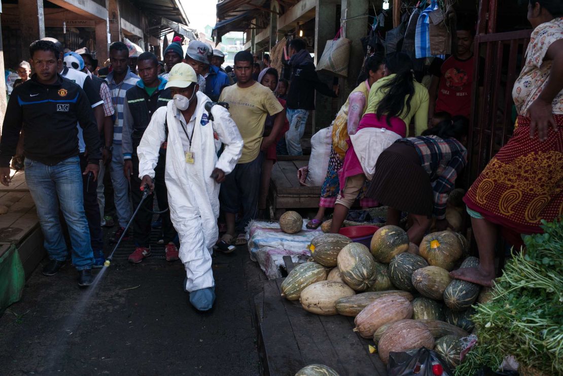 People stand back as a council worker sprays disinfectant during the clean-up of the market of Anosibe in the Anosibe district, one of the most unsalubrious districts of Antananarivo.