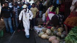 People stand back as a council worker sprays disinfectant during the clean-up of the market of Anosibe in the Anosibe district, one of the most unsalubrious districts of Antananarivo on October 10, 2017.The World Health Organization has warned that a deadly outbreak of the plague, which began in late August, has claimed more than 20 lives in Madagascar and is swiftly spreading in cities across the country. Rats are porters of fleas which spread the bubonic plague and are attracted by garbages and unsalubrity. Pneumonic plague, which is passed through person-to-person transmission, has also been recorded. / AFP PHOTO / RIJASOLO        (Photo credit should read RIJASOLO/AFP/Getty Images)