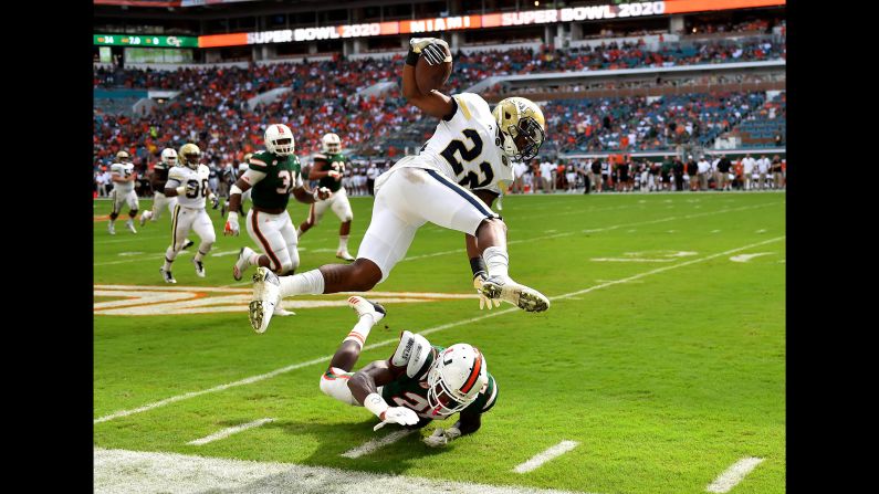 Miami Hurricanes defensive back Michael Jackson leaps over Georgia Tech Yellow Jackets running back Clinton Lynch during the first half of the game on Saturday, October 14, in Miami Gardens, Florida. 