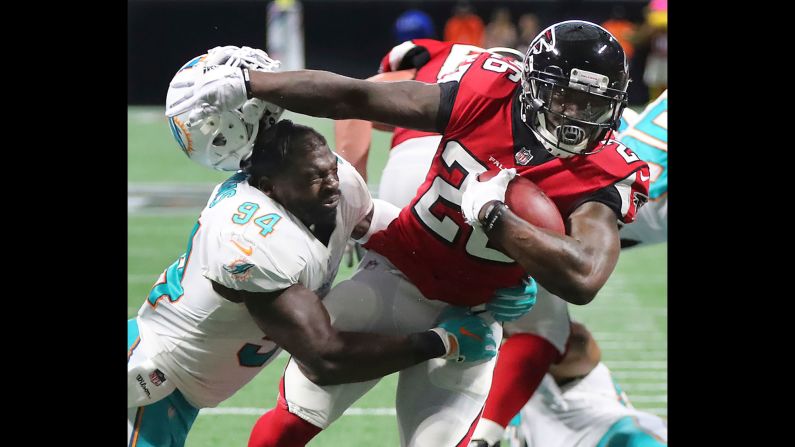 Atlanta Falcons running back Tevin Coleman knocks off Miami Dolphins linebacker Lawrence Timmons' helmet as he breaks the tackle to run for a touchdown during the second half of an NFL football game on Sunday, October 15,  in Atlanta.
