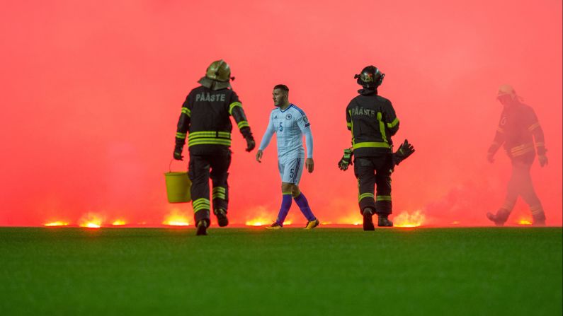 Firefighters run on the pitch to take care of flares thrown by Bosnia fans during the FIFA World Cup 2018 qualification soccer match between Estonia and Bosnia on Tuesday, October 10, in Tallinn, Estonia.     