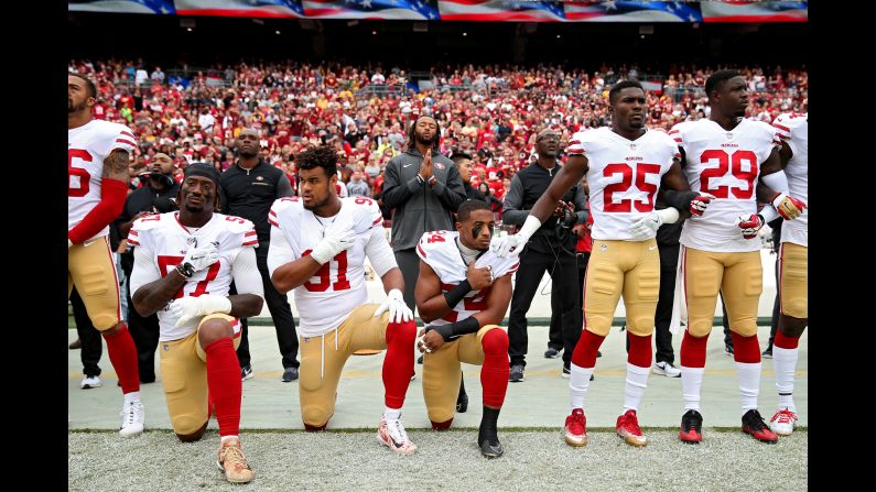 K'Waun Williams, Arik Armstead, and Eli Harold of the San Francisco 49ers kneel while holding their hands over their chest during the National Anthem before playing against the Washington Redskins at FedExField on Sunday, October 15, in Landover, Maryland.