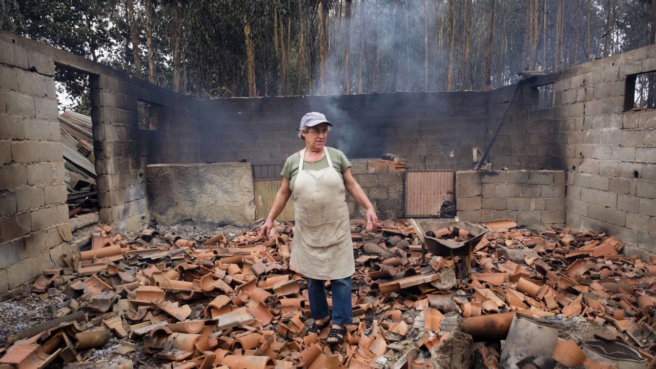 Inocencia Rodrigues, 64, walks among the debris of the burnt shed where she raised chickens and pigs in the village of Sao Joaninho in northern Portugal.