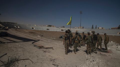 Soldiers of SDF reaching inside of stadium to put the flag.Syria, Raqqah - October 17, 2017