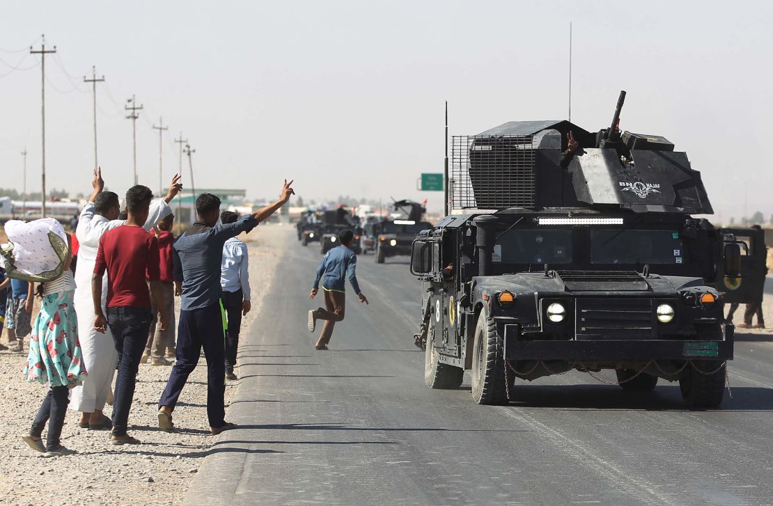 Locals wave to Iraqi forces as they arrive in southern Kirkuk on Monday.
