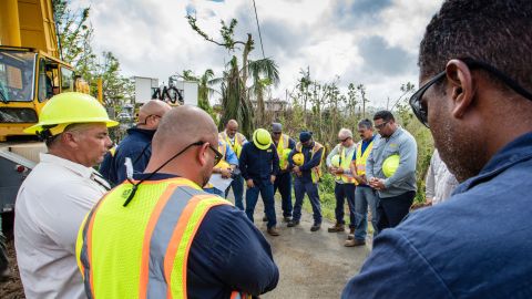 A team working to restore power lines prays by a transmission tower they are getting back up.