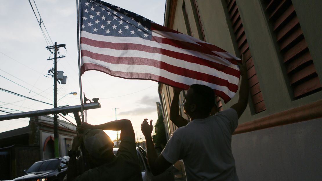 US Army Reserve soldiers, from Puerto Rico, attach an American flag to one of their vehicles in Yauco, Puerto Rico.