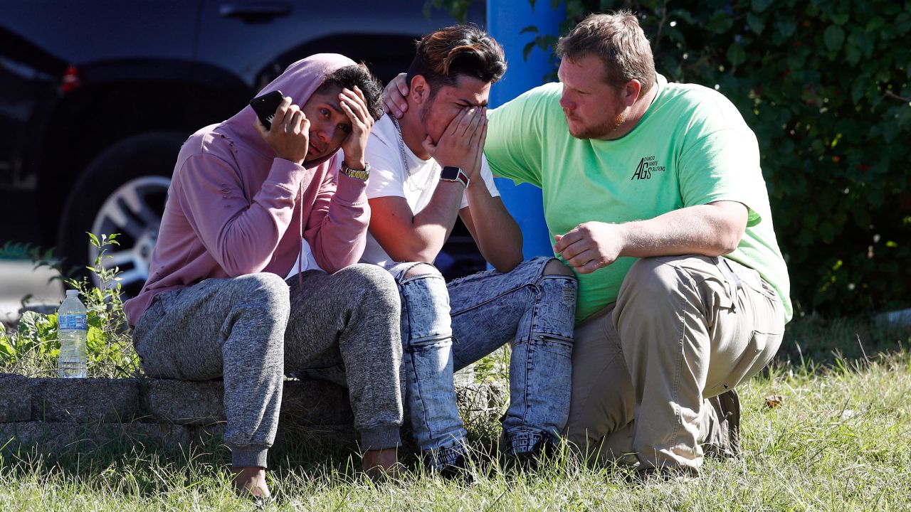 People gather across the street from the scene of a shooting at a business park in the Edgewood area on Wednesday.