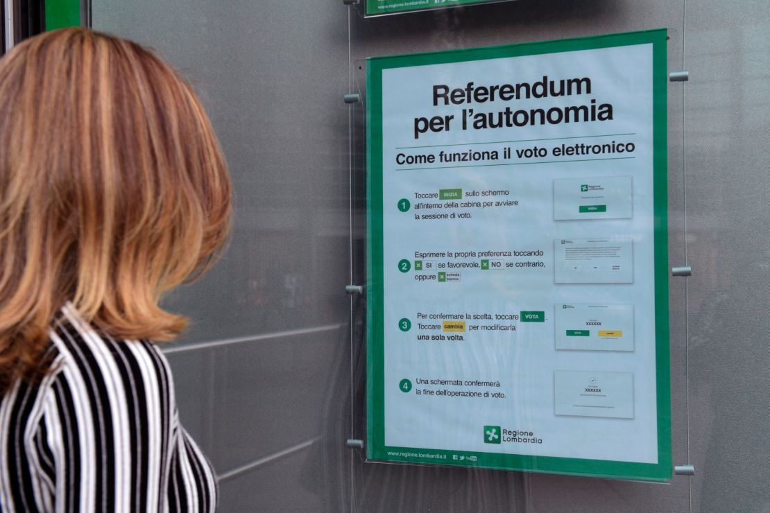 A woman in Milan looks at a poster explaining how to vote in Sunday's referendum.