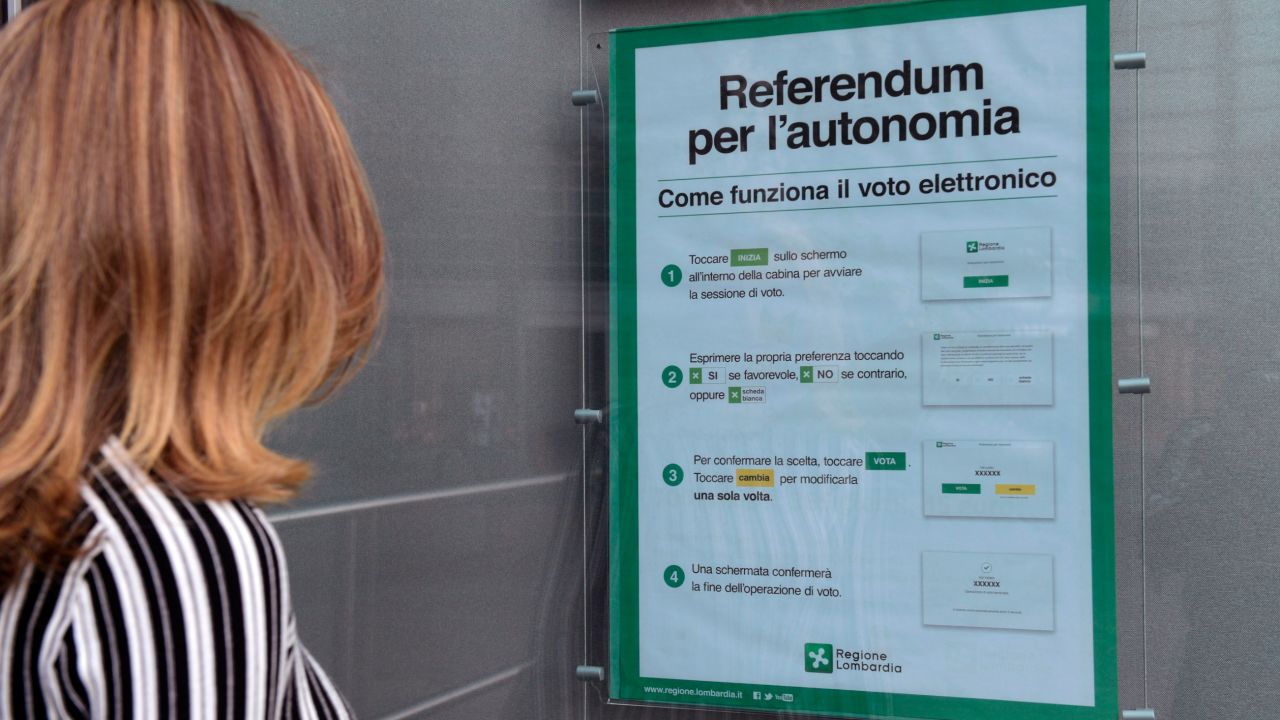 A woman in Milan looks at a poster explaining how to vote in Sunday's referendum.