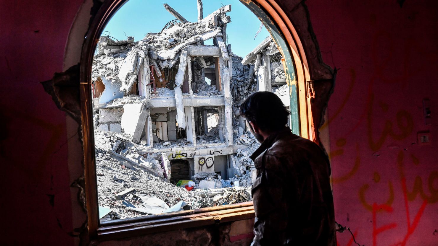 A member of the Syrian Democratic Forces, backed by US special forces, looks out from a building at the front line in Raqqa on October 16, 2017.