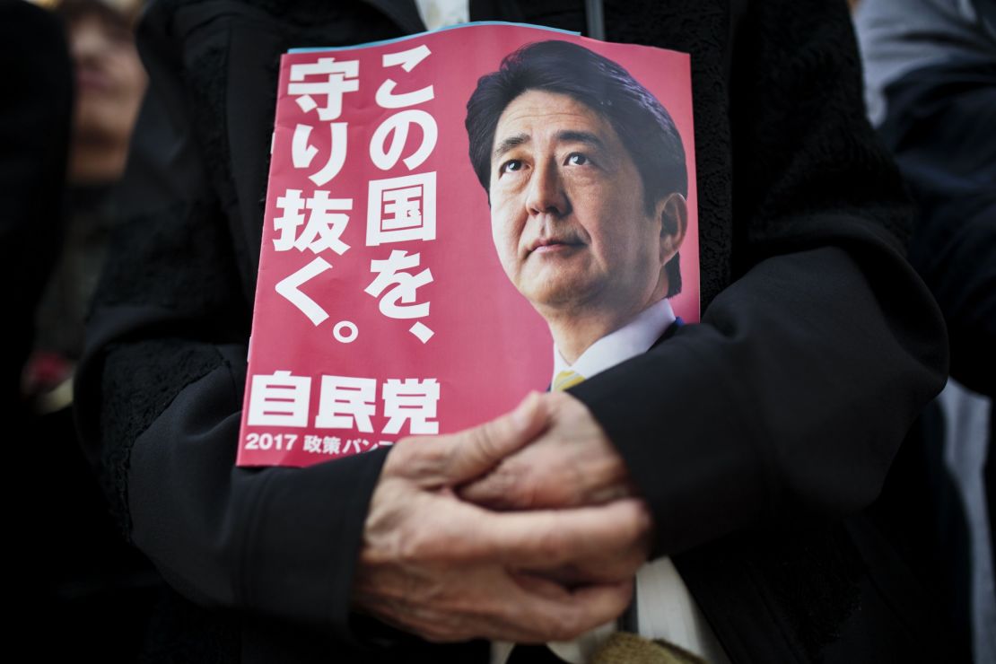 A man holds an electoral leaflet urging votes for Japan's Prime Minister Shinzo Abe during an election campaign in Saitama, October 18.