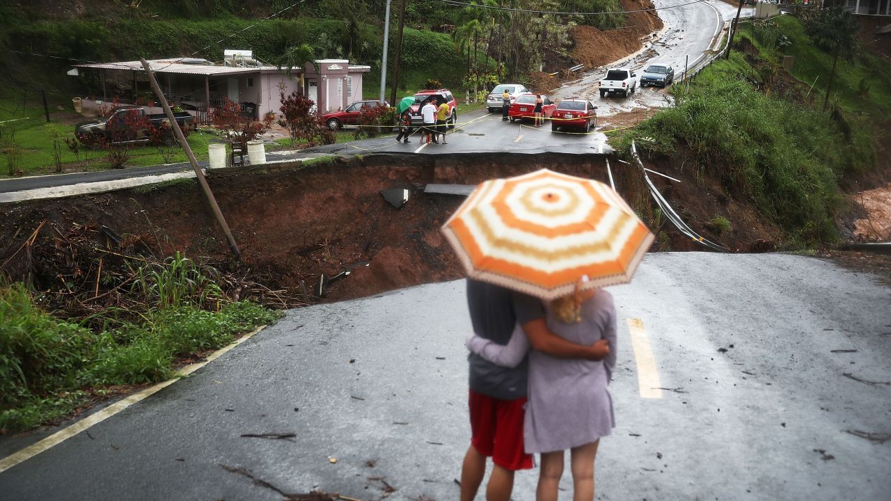 BARRANQUITAS, PUERTO RICO - OCTOBER 07: People look on at a section of a road that collapsed and continues to erode days after Hurricane Maria swept through the island on October 7, 2017 in Barranquitas, Puerto Rico. Puerto Rico experienced widespread damage including most of the electrical, gas and water grid as well as agriculture after Hurricane Maria, a category 4 hurricane, passed through. (Photo by Joe Raedle/Getty Images)