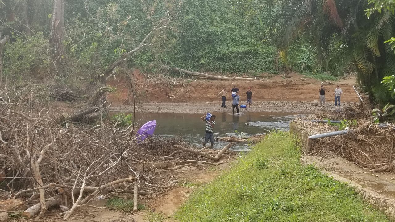 The "Añasco Expendables" carry supplies to the community across the Hondo River 