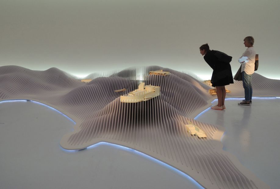 Visitors to the "Endeavors" exhibition inspect the giant model of Naoshima island.
