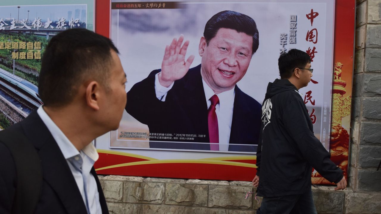 TOPSHOT - People walk past a poster featuring Chinese President Xi Jinping with a slogan reading "Chinese Dream, People's Dream" beside a road in Beijing on October 16, 2017. 
As Chinese leader Xi Jinping prepares to embark on a second five-year term this week, the impulsive leaders of North Korea and the United States could spoil his party. / AFP PHOTO / GREG BAKER        (Photo credit should read GREG BAKER/AFP/Getty Images)
